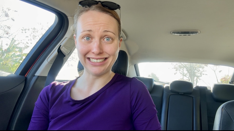 Woman sitting in her car, grimacing in fear and courage in anticipation of the action she is about to take.