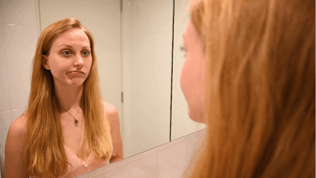 At war with my PMDD self - photo of me looking back at myself in a mirror dissatisfied 