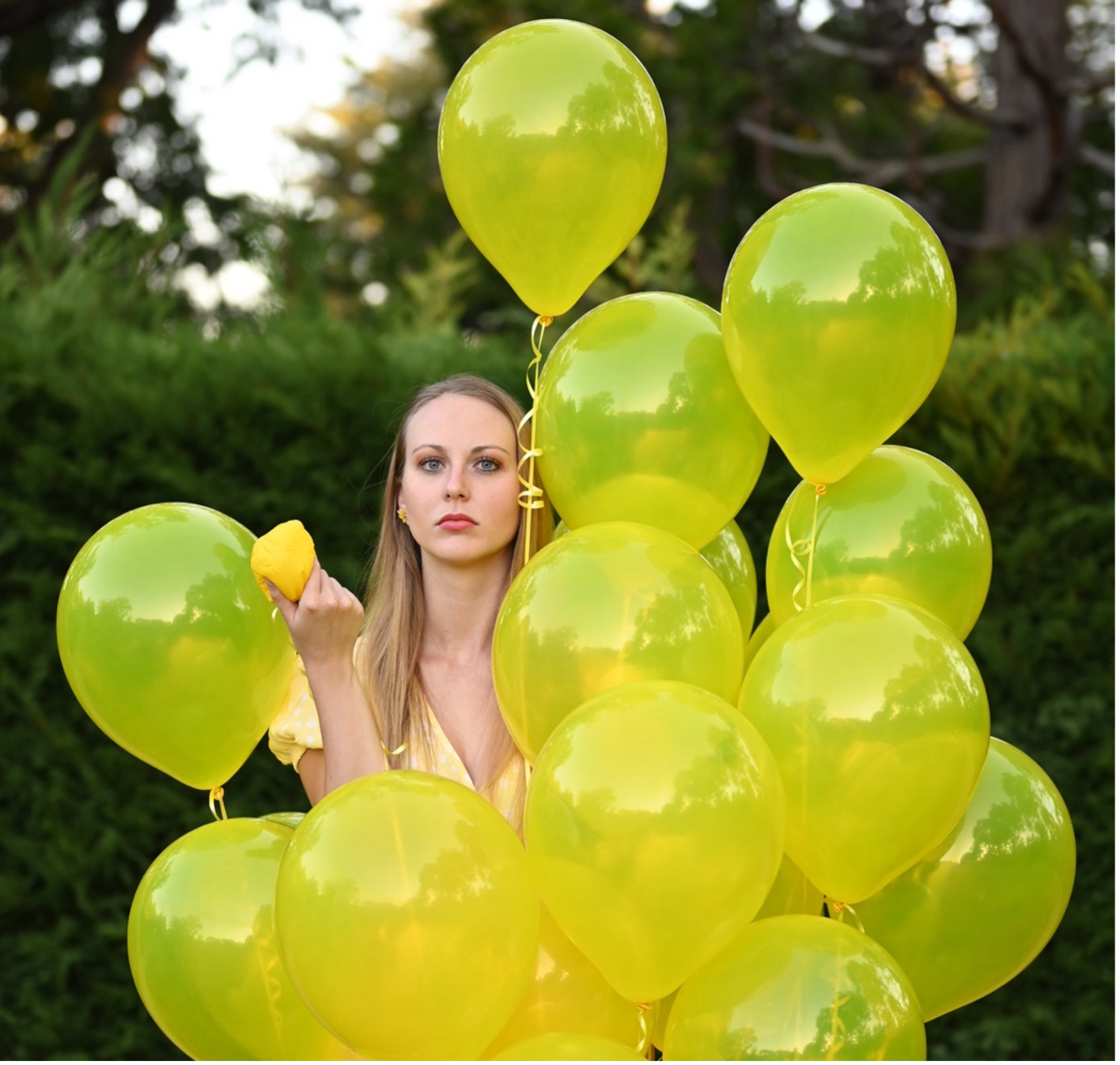 holding a shrivelled balloon, suggesting women's eggs or fertility whilst looking stern because woman, you must advocate for yourselves