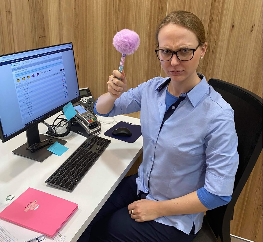 sat at an office chair in a medical center behind the desk with a fuzzy pen and notepad, writing it all down. 