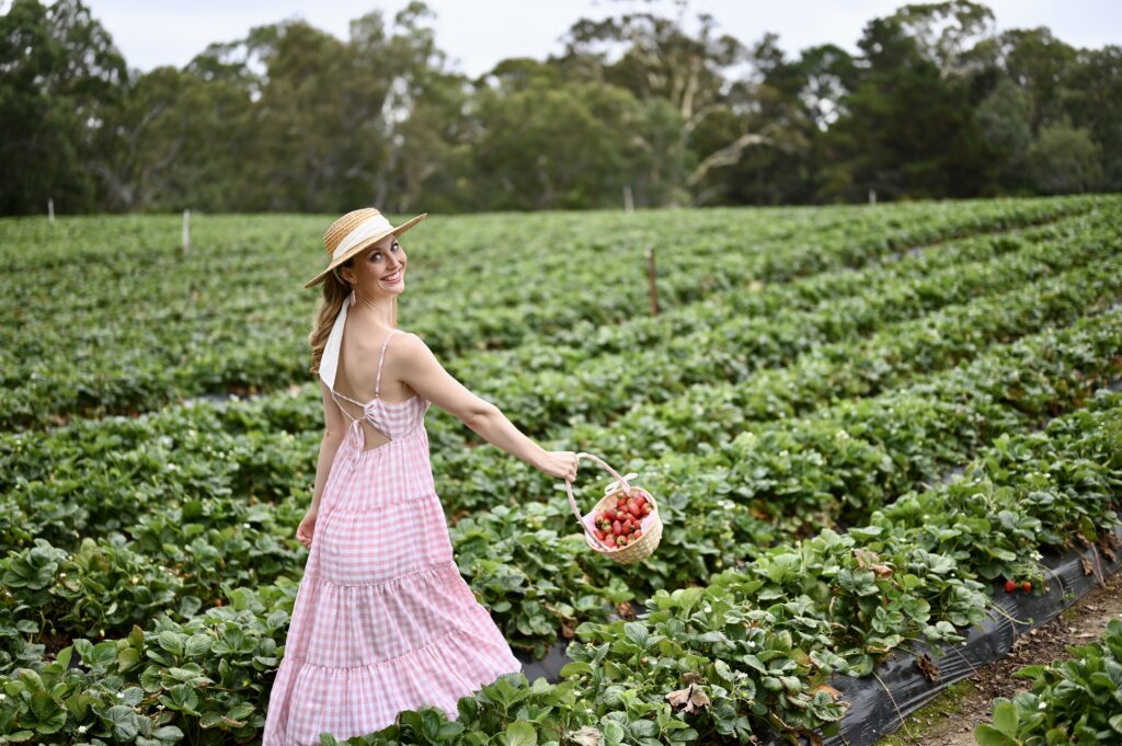 Victoria-Rose Paris swinging basket of strawberries wearing a hat at Beerenberg Strawberry picking farm.